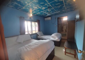 Una habitación con dos camas, ventilador de techo y ventana con cortinas.