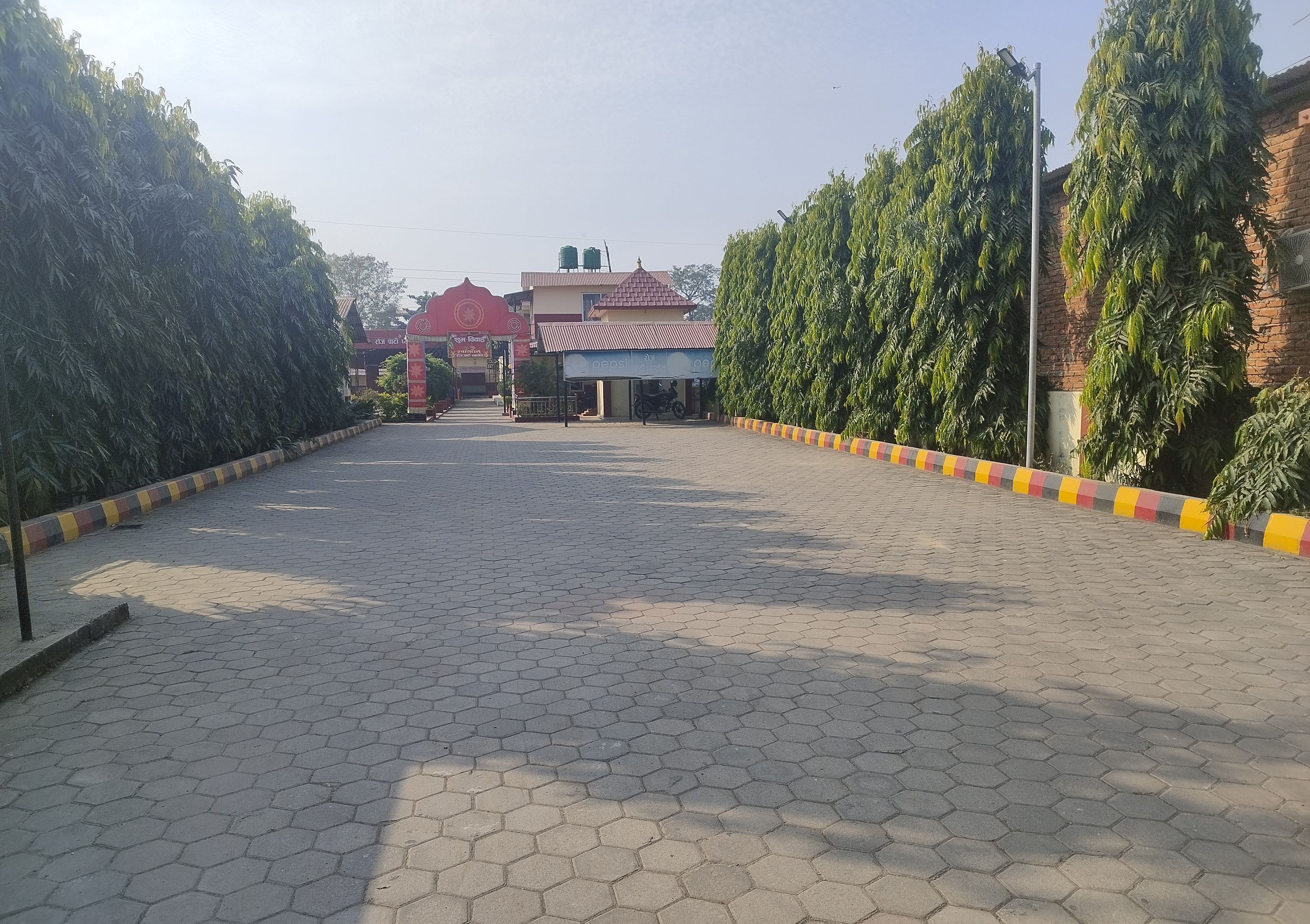 A paved walkway leading to a building with a red roof and a signboard.