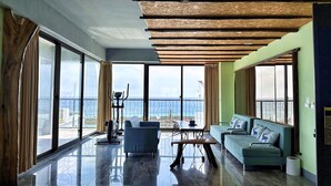 A spacious living area with a view of the sea, a ceiling with exposed wooden beams, and a modern sofa. - Kenting Singhaiwan (Hengchun)