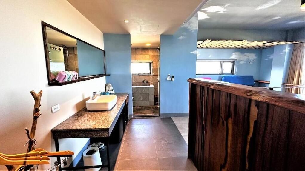 A narrow hallway leading to a bathroom with a sink and mirror.
