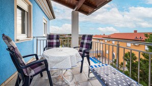 Een balkon met een tafel en stoelen, uitzicht op de omgeving en een heldere lucht.