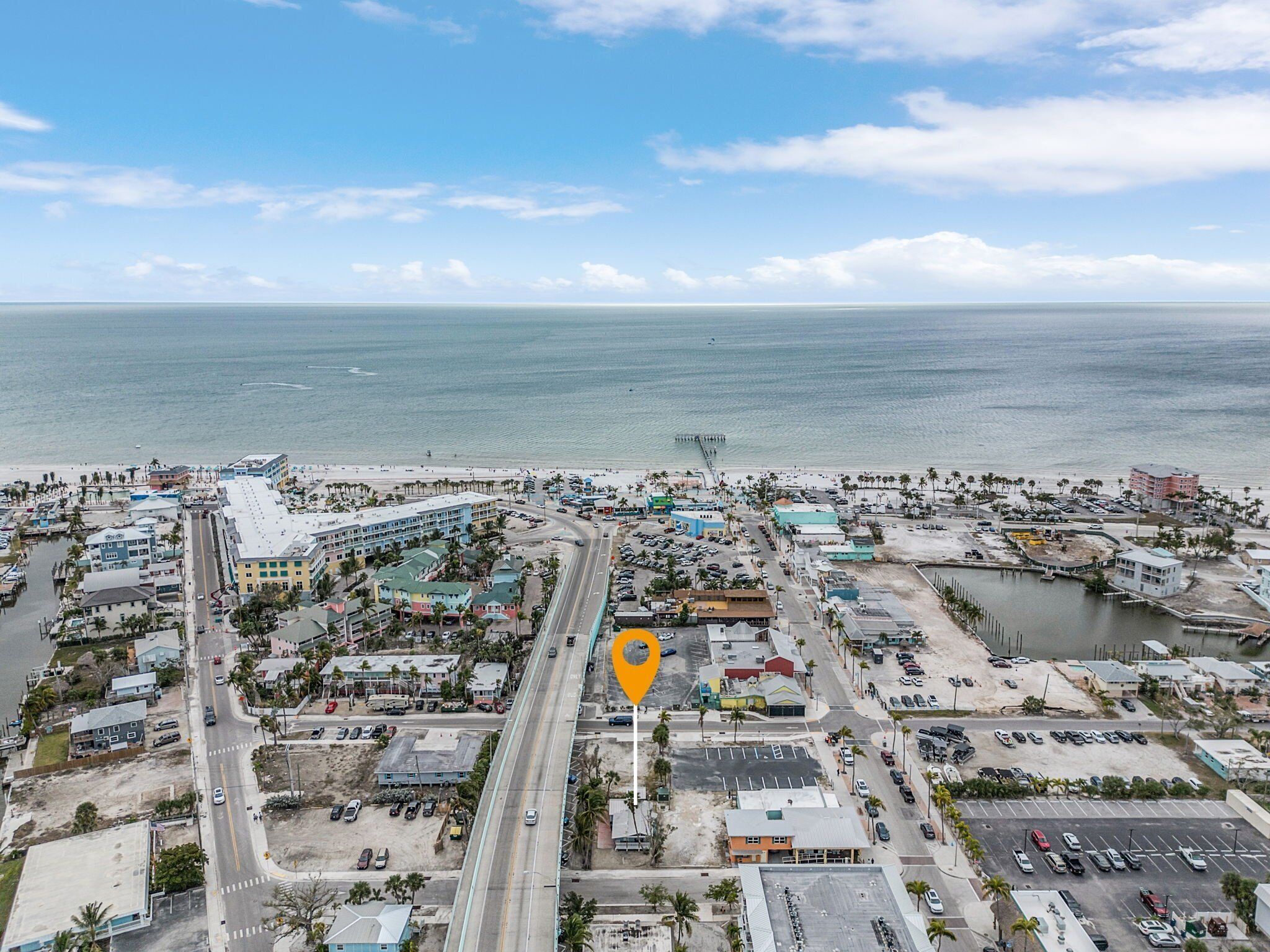 An aerial view of a coastal town with a prominent road, buildings, and a beach.