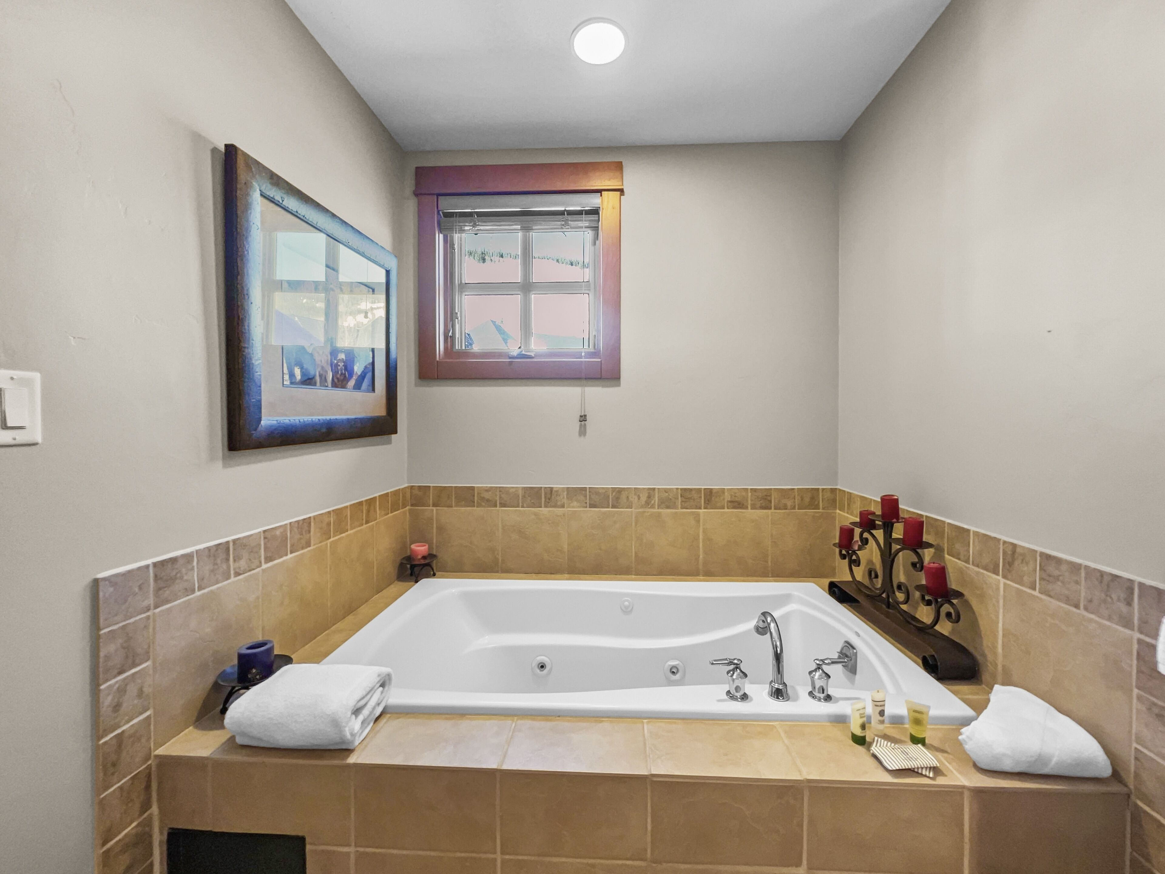 Un baño con una bañera grande, una ventana y un cuadro enmarcado en la pared.