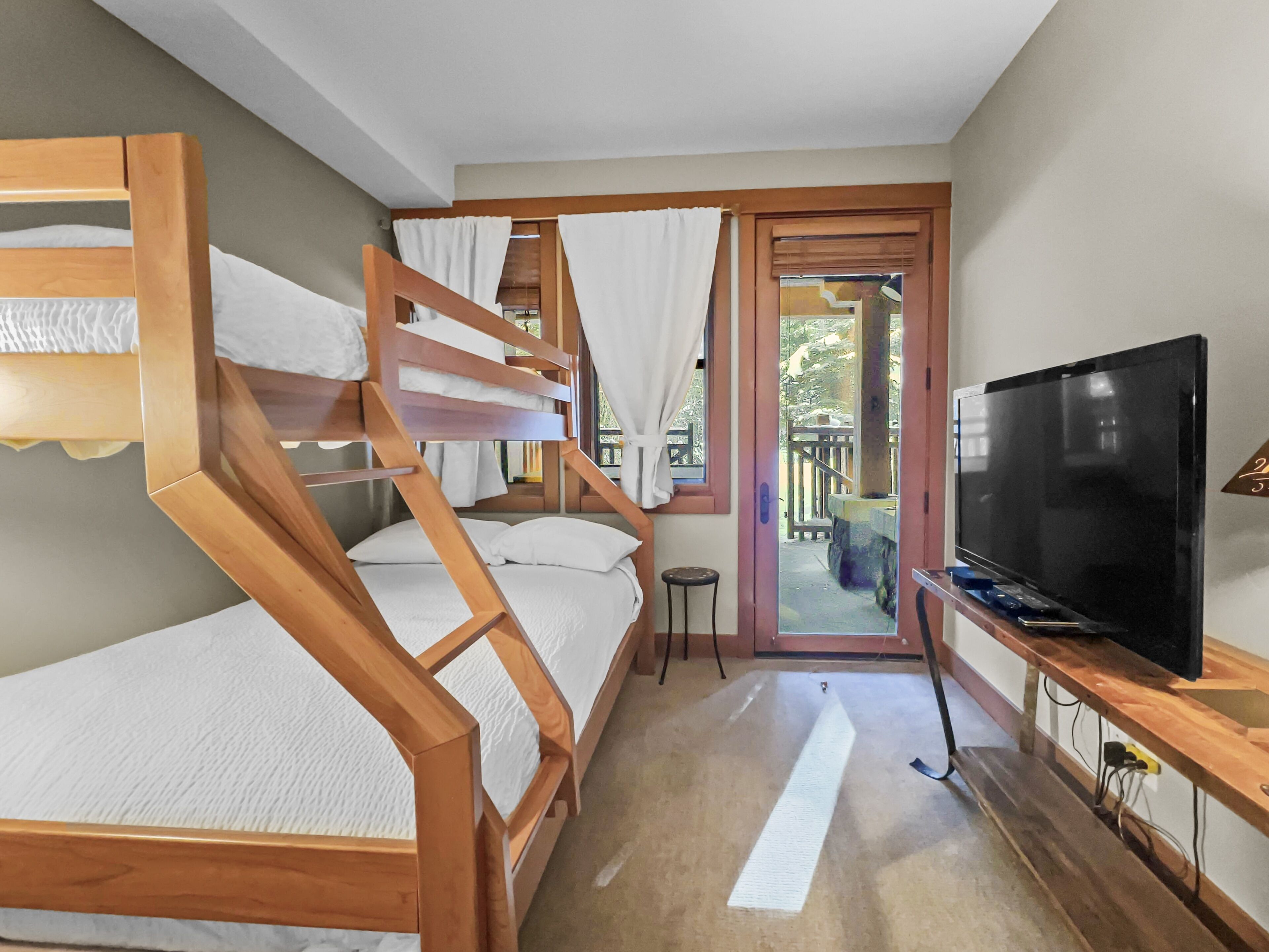 Una habitación con literas, televisión y vista al exterior.