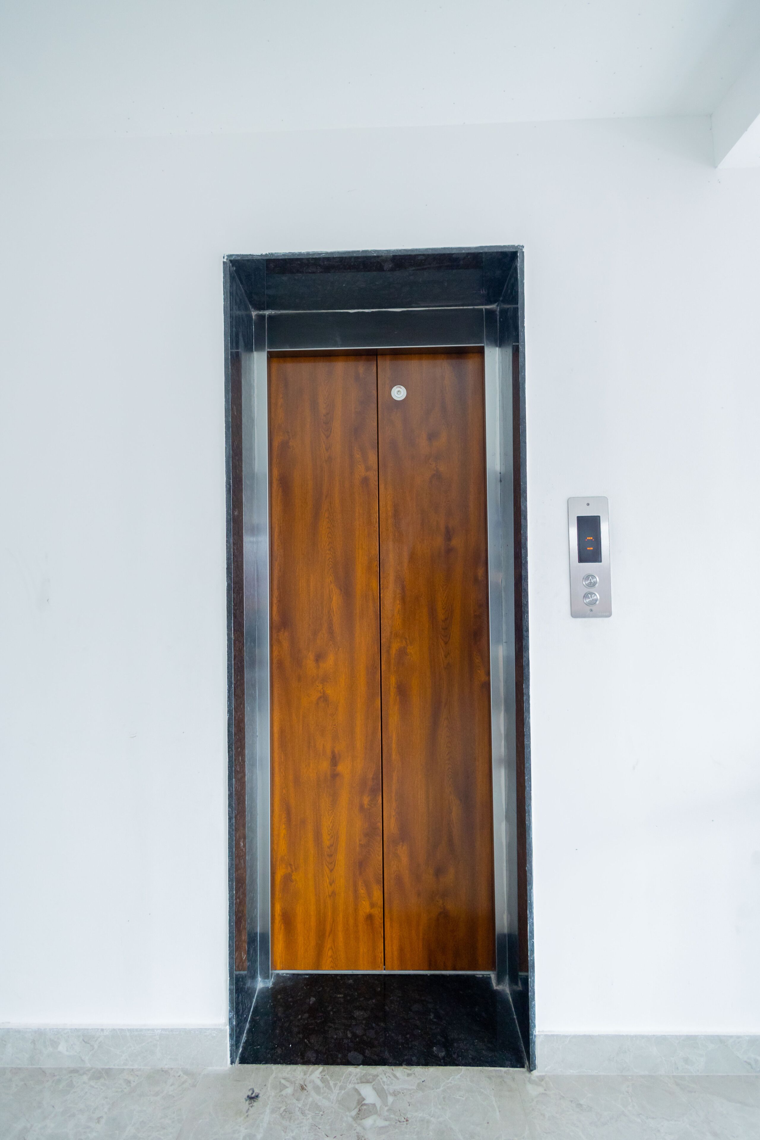 Porta de elevador de madeira com um painel de exibição digital ao lado.