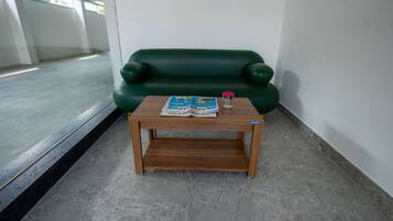 Un sofá verde y una mesa de madera con una revista y un vaso de agua.