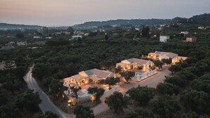 A large estate with multiple buildings, surrounded by dense greenery and a winding road.