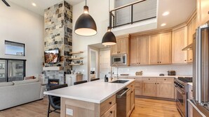 A modern kitchen with wooden cabinets, a central island, a microwave, and a stove. - Moose Mgmt at Mayflower Lakeside 1032: Central AC-Pvt Hot Tub-BBQ- Two King Beds (Park City)
