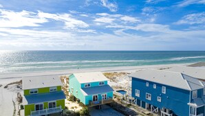A beachfront property with colorful houses, a sandy beach, and the ocean in the background.