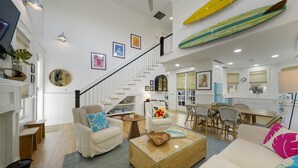 A spacious living area with a staircase, a dining area, and a kitchen. - Designer Home in Seaside, FL! Walk to Pool and Beach + 2 Adult Bikes! (Santa Rosa Beach Fl)