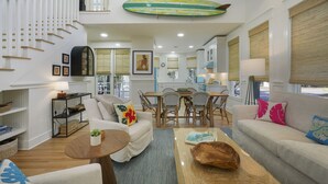 A spacious living area with a staircase, dining table, and seating. - Designer Home in Seaside, FL! Walk to Pool and Beach + 2 Adult Bikes! (Santa Rosa Beach Fl)