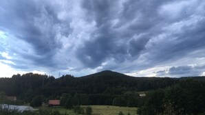 Maaseutumaisema, jossa on vuori, pelto ja muutama rakennus.