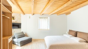 A bedroom with a wooden ceiling, a bed with beige bedding, a grey sofa, and a wooden wardrobe. - LP4                                                                              (Orino)