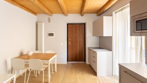A modern kitchen with wooden beams, a dining area with a wooden table and white chairs, and a built-in microwave. - LP4                                                                              (Orino)