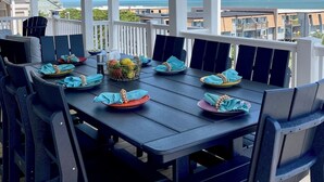 A covered outdoor dining area with a view of the ocean and buildings in the background. - New 8BR/7.5BA with Spectacular Ocean View, Elevator, Private Heated Pool (Ocean Isle Beach)