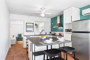 A modern kitchen with a central island, stainless steel appliances, and a teal accent wall.