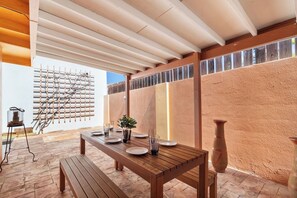 An outdoor dining area with a wooden table set for two, a grill, and a decorative wall with vertical elements. - 3BR Home w/ Private Pool & Gazebo, Noord (Noord)