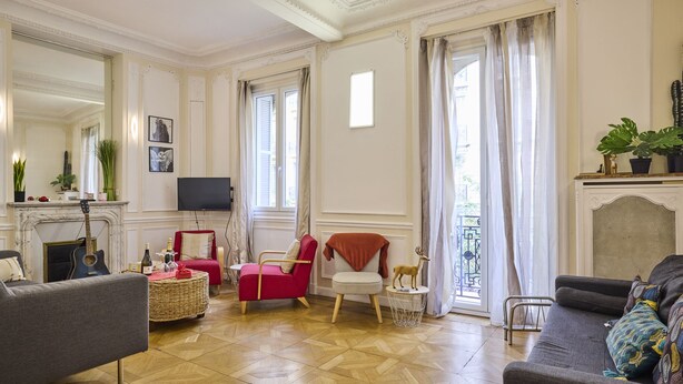 Ein geräumiges Wohnzimmer mit Kamin, Fernseher und einem Balkon mit Vorhängen.