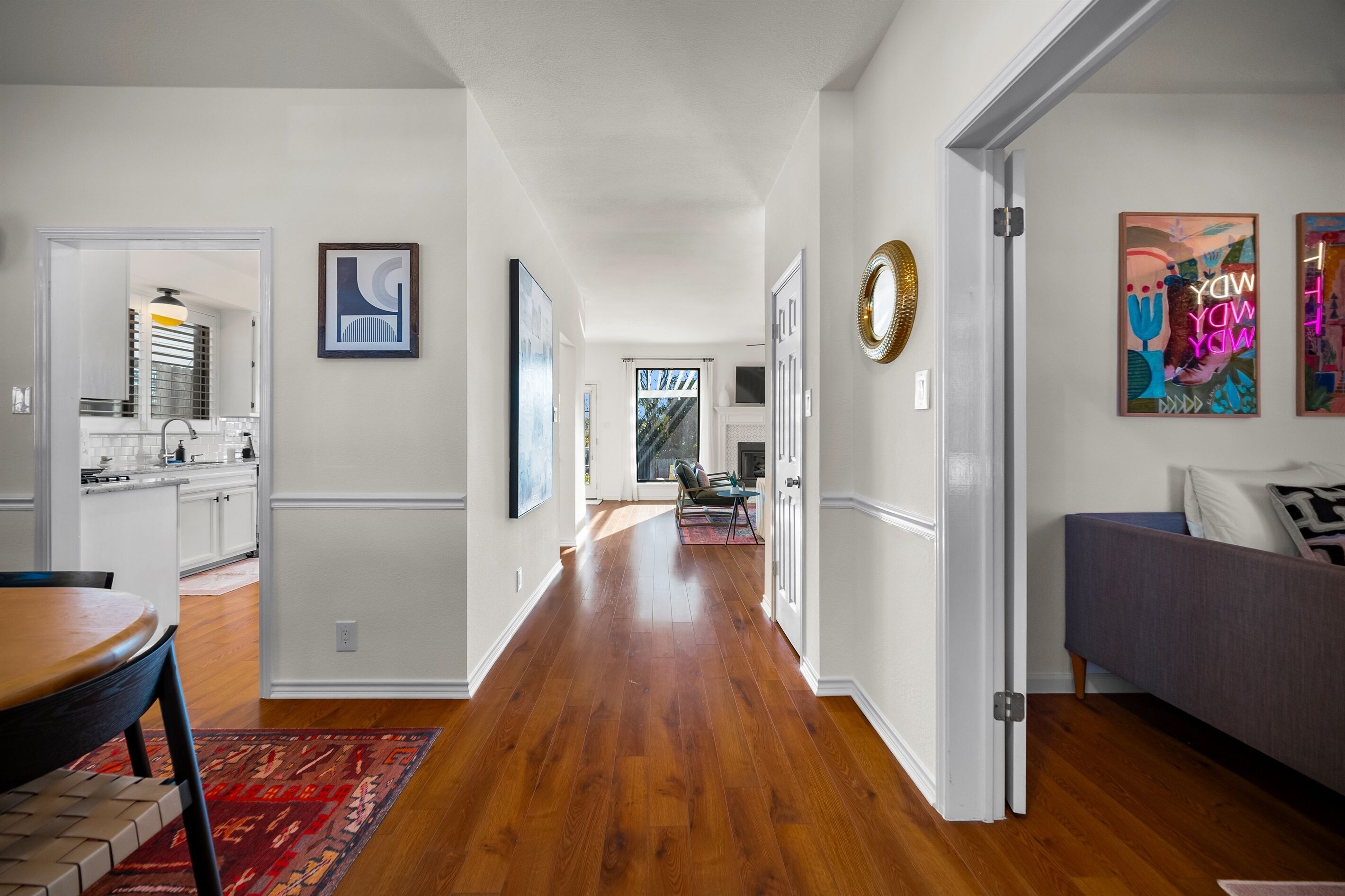 A modern interior with a wooden floor, white walls, and a dining area with a table and chairs.