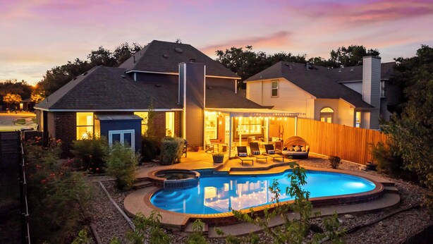 A two-story house with a swimming pool, a covered patio, and a fenced backyard.