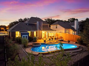 Une maison à deux étages avec une piscine, un patio couvert et une cour arrière clôturée.