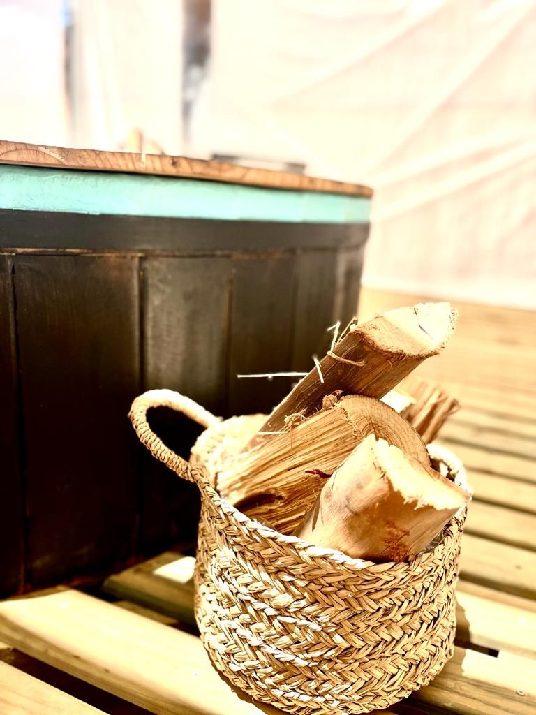 A woven basket with a handle containing a piece of wood and a log.