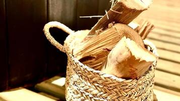 A woven basket with a handle containing a piece of wood and a log.