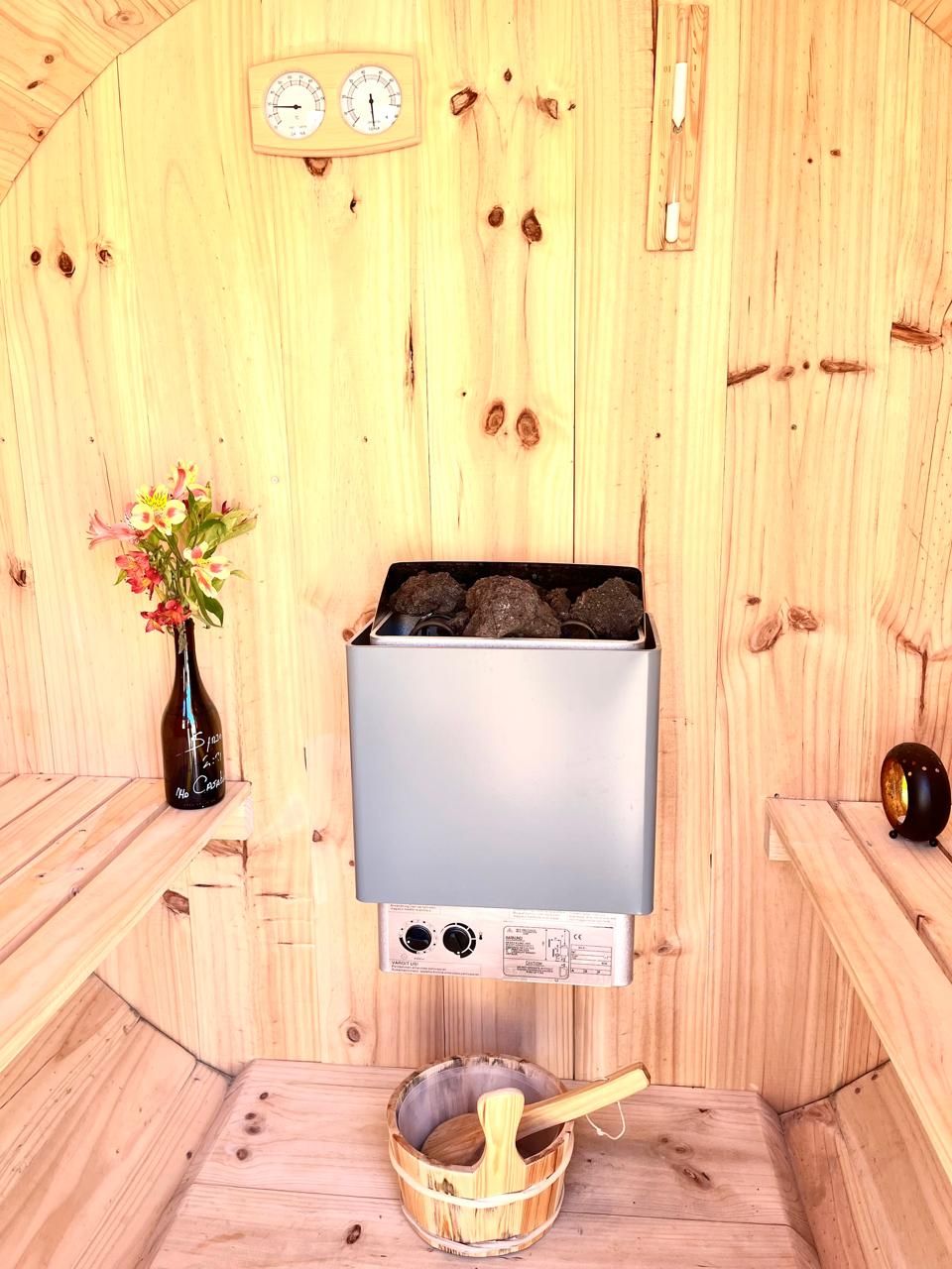 Una sauna con paredes de madera, un reloj y un recipiente de madera con una cuchara.