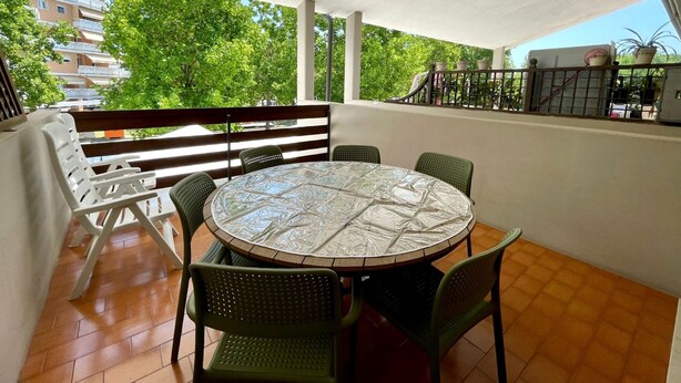 A round table with chairs on a balcony with a view of trees and buildings. - Spacious Duplex Near the Beach (Caorle)