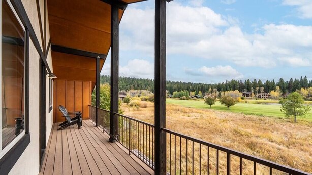 A wooden deck with a view of a grassy field and trees. - Stylish 4bed/4bath Retreat! (McCall)