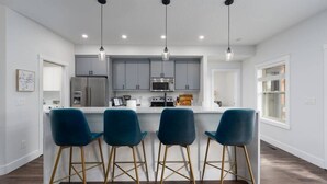 A modern kitchen with a central island, bar stools, and pendant lighting. - Stylish 4bed/4bath Retreat! (McCall)