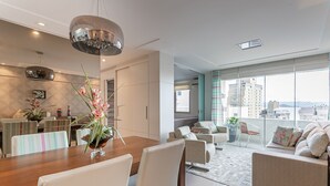 Ein modernes Wohnzimmer mit Essbereich, großen Fenstern und Blick auf die Stadt.