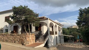 A two-story house with a stone wall, a staircase, and a patio area with outdoor furniture. - 75 m² indépendant villa in Abbiadori, costa smeralda, Sardinia (Abbiadori)