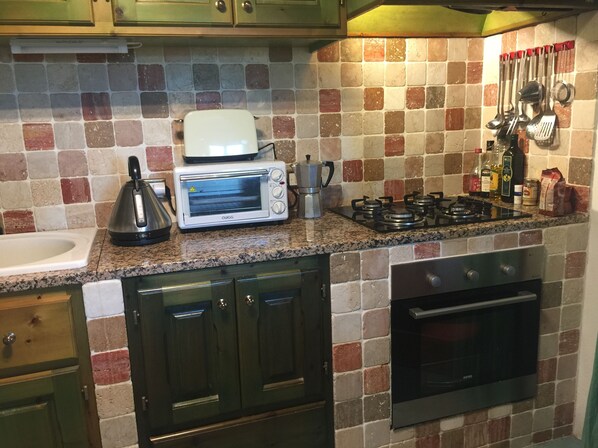 A kitchen with a microwave, toaster, gas stove, and various kitchen utensils. - 75 m² indépendant villa in Abbiadori, costa smeralda, Sardinia (Abbiadori)
