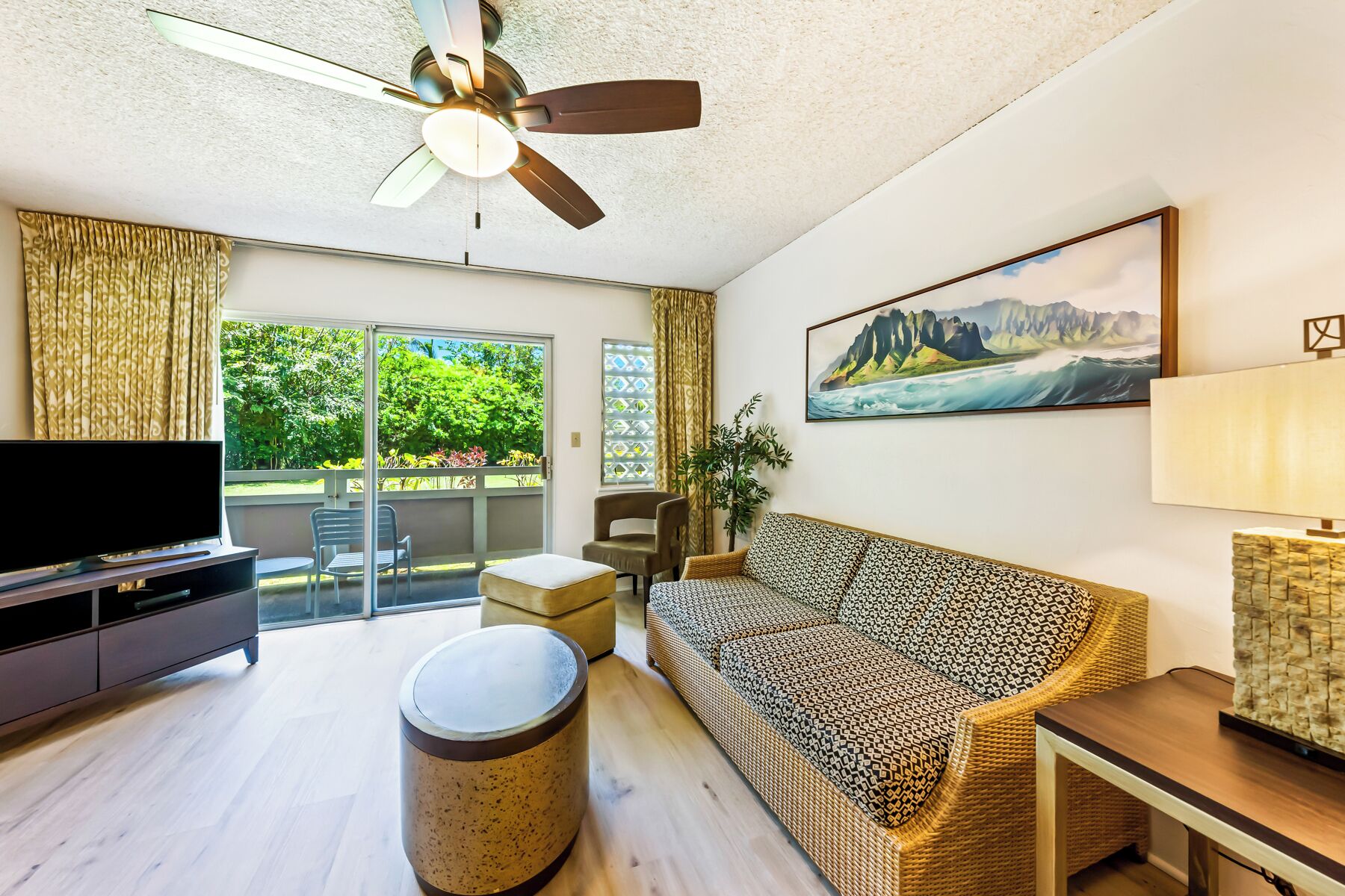 Ein Wohnzimmer mit Flachbildfernseher, einer Couch, einem Couchtisch und einem Deckenventilator.