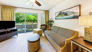 Ein Wohnzimmer mit Flachbildfernseher, einer Couch, einem Couchtisch und einem Deckenventilator.