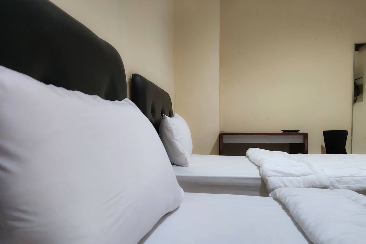 A hotel room with a bed, a nightstand, and a chair.