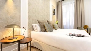 A neatly made bed with pillows, a bedside lamp, and a magazine on the bed. - Genteel Home Capiteles (Granada)