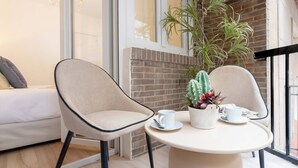 A modern room with a white sofa, two chairs, a small round table, and a potted plant.