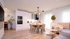 A modern kitchen with white cabinets, a dining table with four chairs, and a central island.