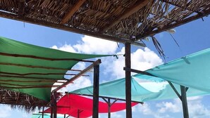 Una playa con estructuras de madera y sombrillas de colores que dan sombra.