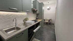 A modern kitchen with grey cabinets, a stainless steel sink, and a built-in oven. - ADORABLE two-bedroom apartment close to Vatican City (Roma)
