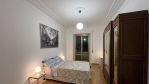 A bedroom with a bed, bedside table, lamp, and a door leading to a balcony. - ADORABLE two-bedroom apartment close to Vatican City (Roma)