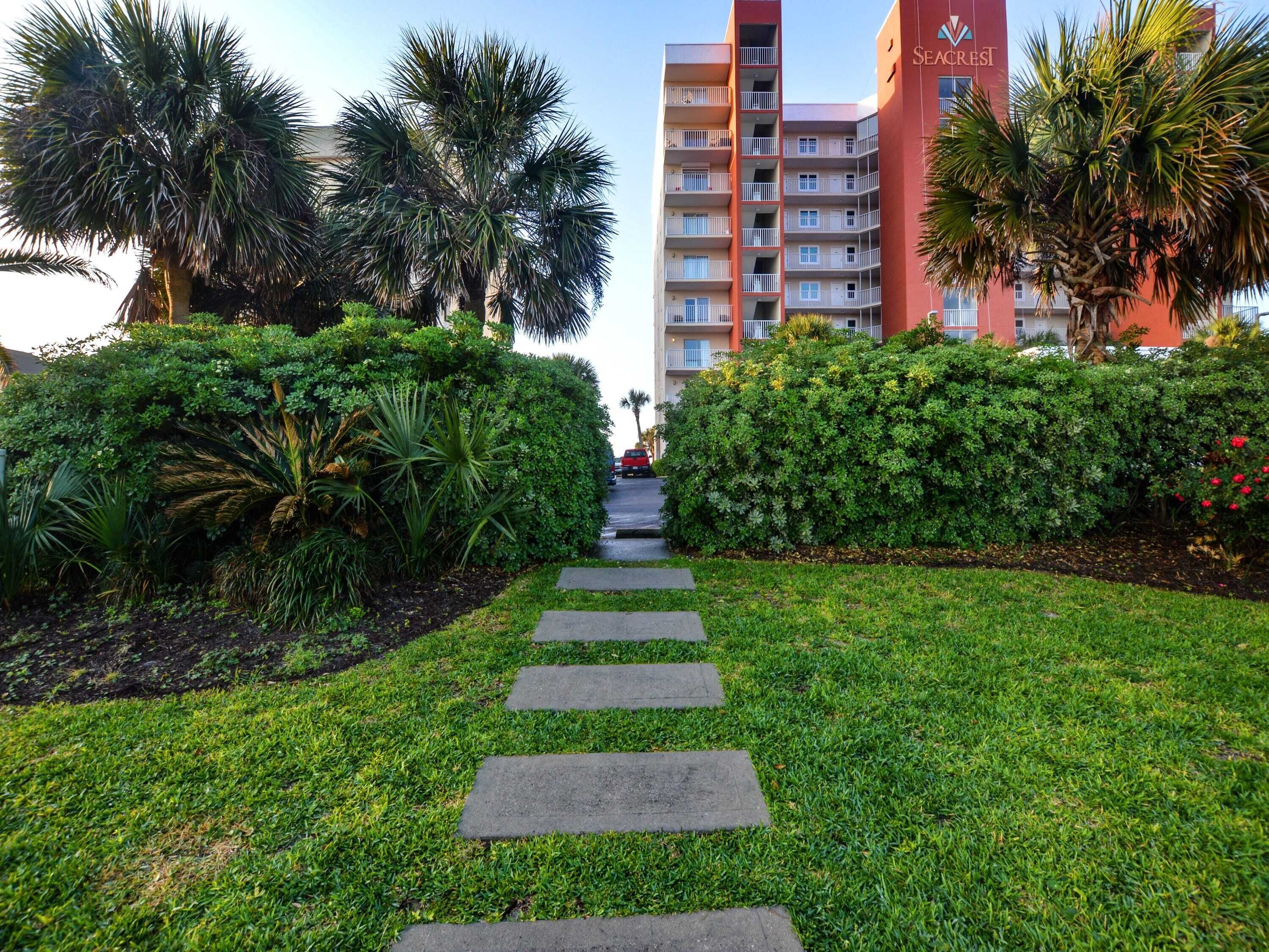 A pathway leading to a hotel with a red facade and balconies.