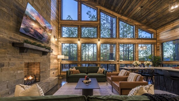 A spacious living area with a stone fireplace, large windows, and a cozy seating arrangement.