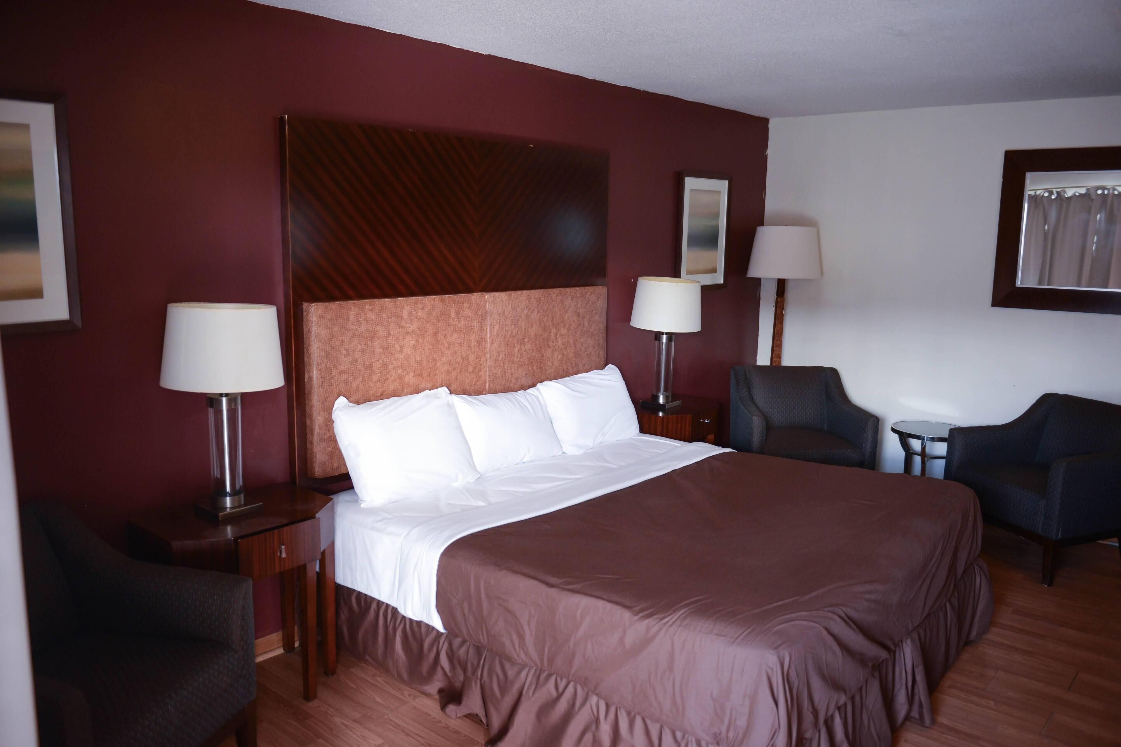 A hotel room with a large bed, two bedside tables with lamps, a chair, and a small table.