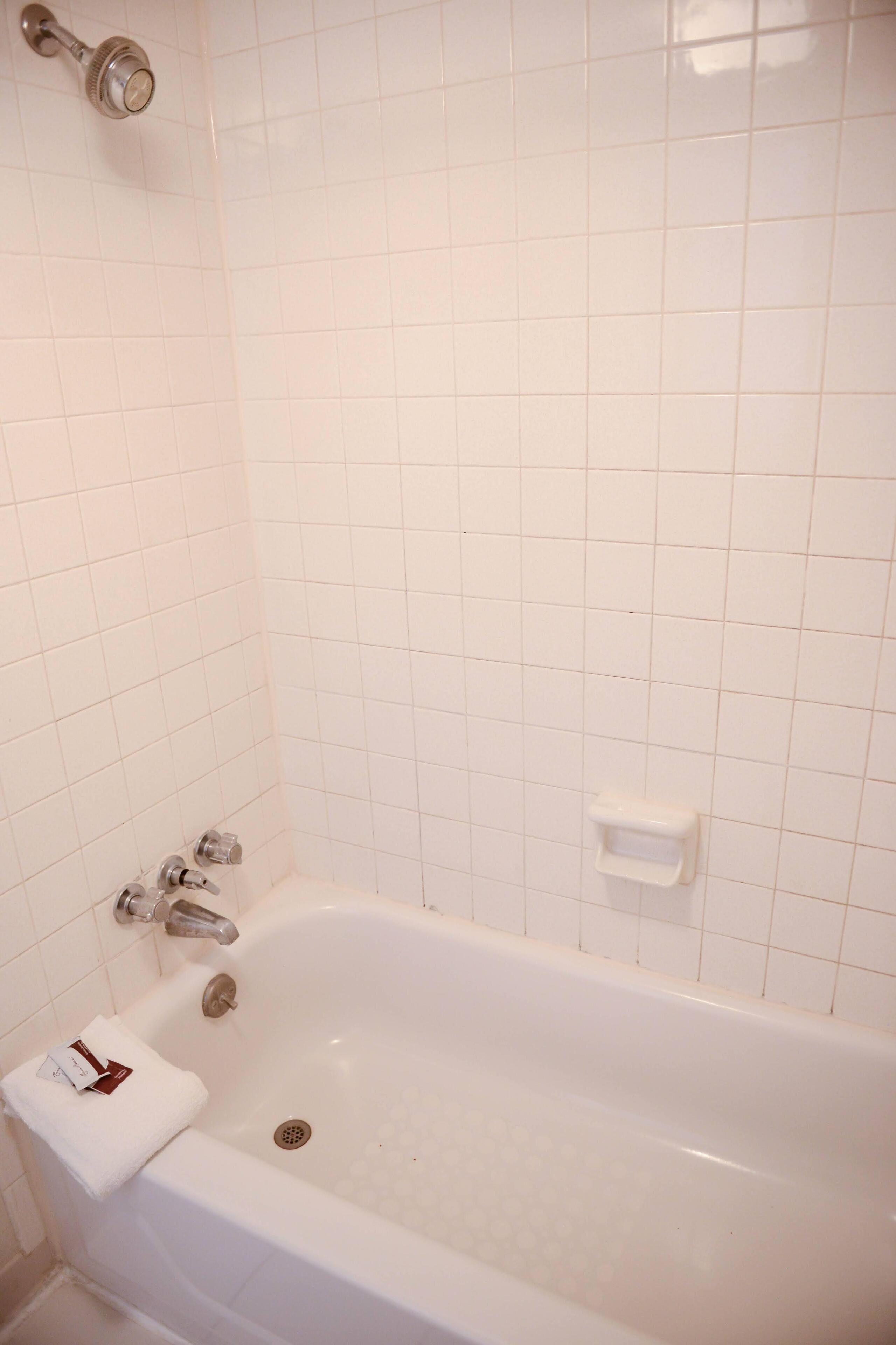 Una vasca da bagno bianca con una doccetta, un asciugamano e un portasapone.