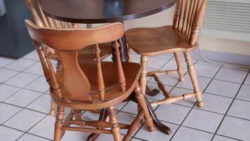 Uma mesa de jantar com duas cadeiras de madeira, um vaso com flores e um mural ao fundo.
