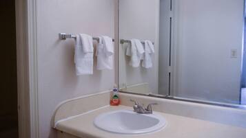 A bathroom with a white sink, a mirror, and a towel rack with several white towels.