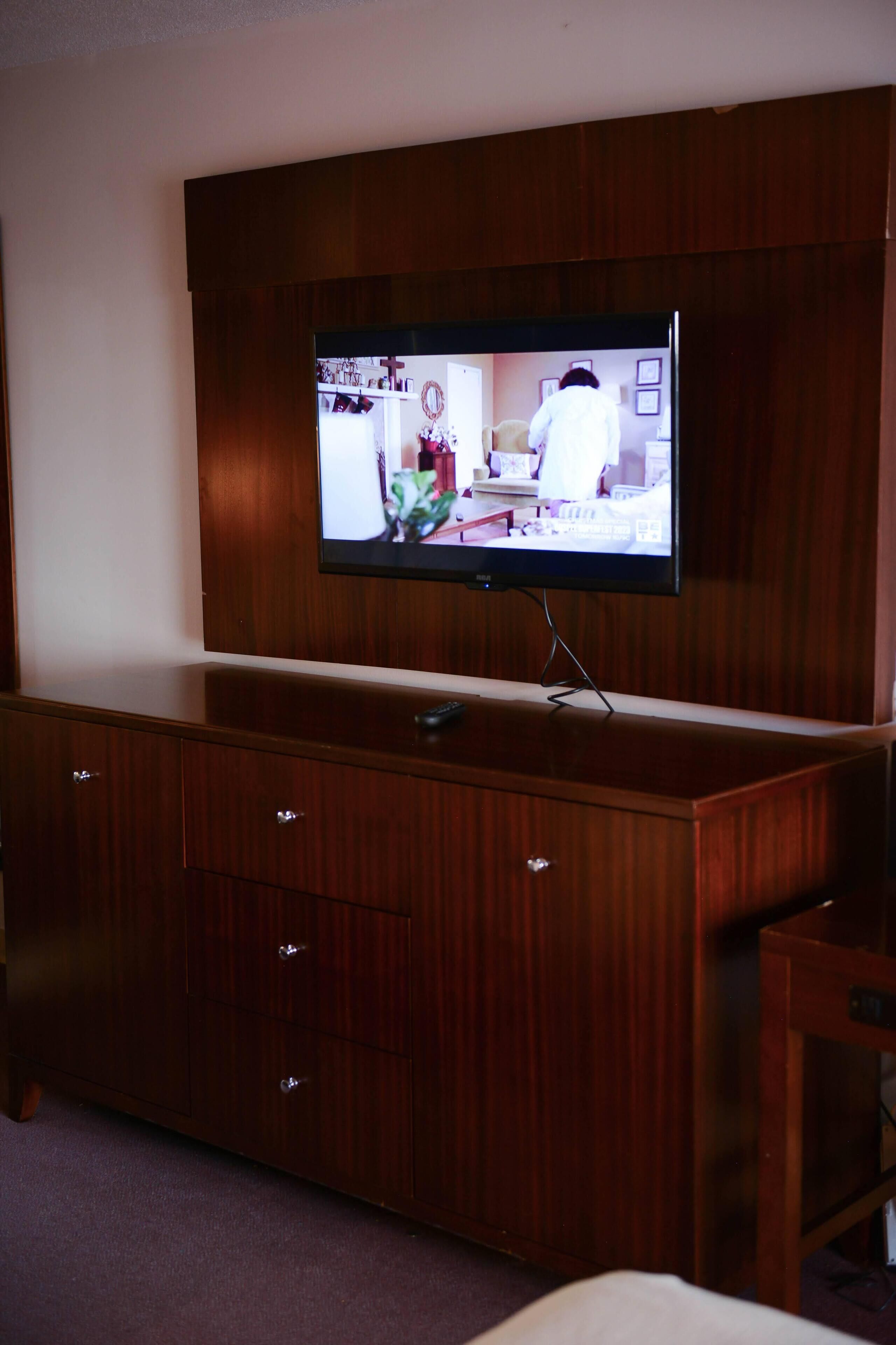 A wooden entertainment center with a flat-screen TV mounted above it.
